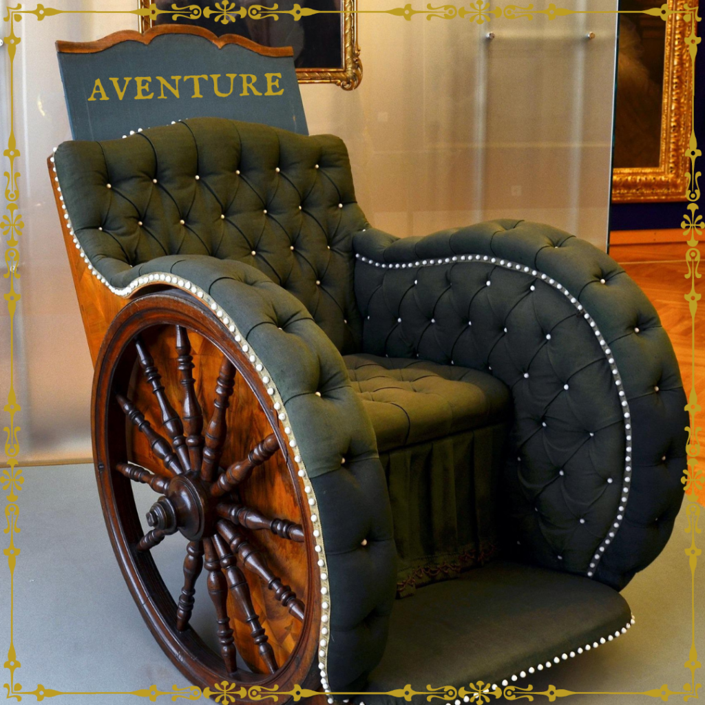 fauteuil roulant à l'esthétique ancienne, en bois et capitonné comme un fauteuil de salon, dont les roues ressemblent à des gouvernails de navire